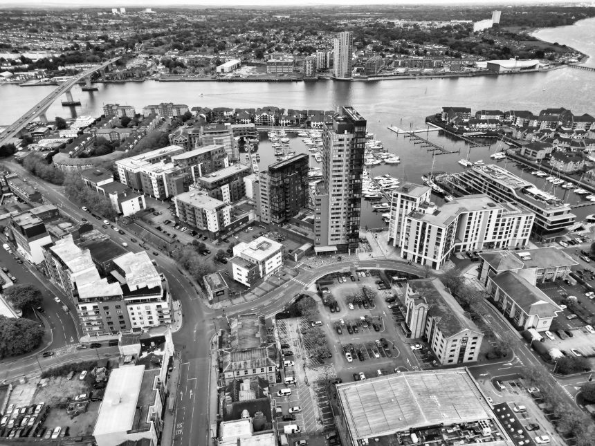 Vista aérea em preto e branco da marina de Southampton, com barcos atracados e a área urbana à margem da água.