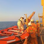 Tripulantes usando equipamentos de proteção preparam um bote salva-vidas durante um exercício de segurança marítima a bordo de um navio.