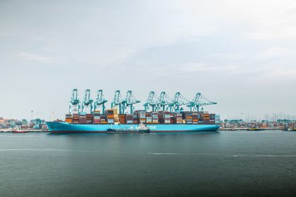 Grande navio porta-contêineres carregado atracado em um porto industrial.