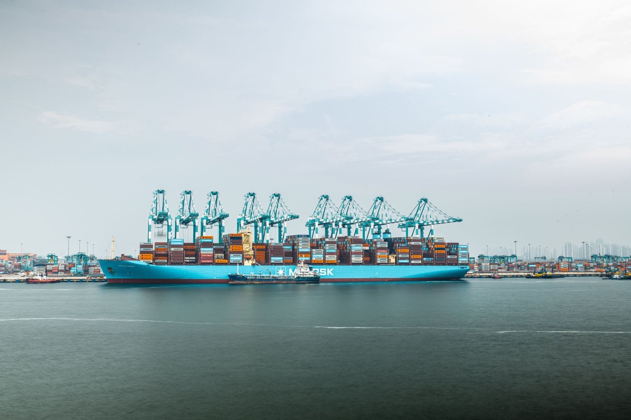 Grande navio porta-contêineres carregado atracado em um porto industrial.