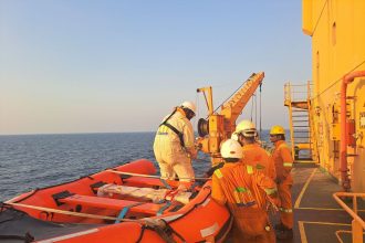 Tripulantes usando equipamentos de proteção preparam um bote salva-vidas durante um exercício de segurança marítima a bordo de um navio.