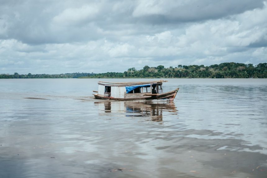 Embarcação tradicional de madeira navegando por um rio na Amazônia brasileira.