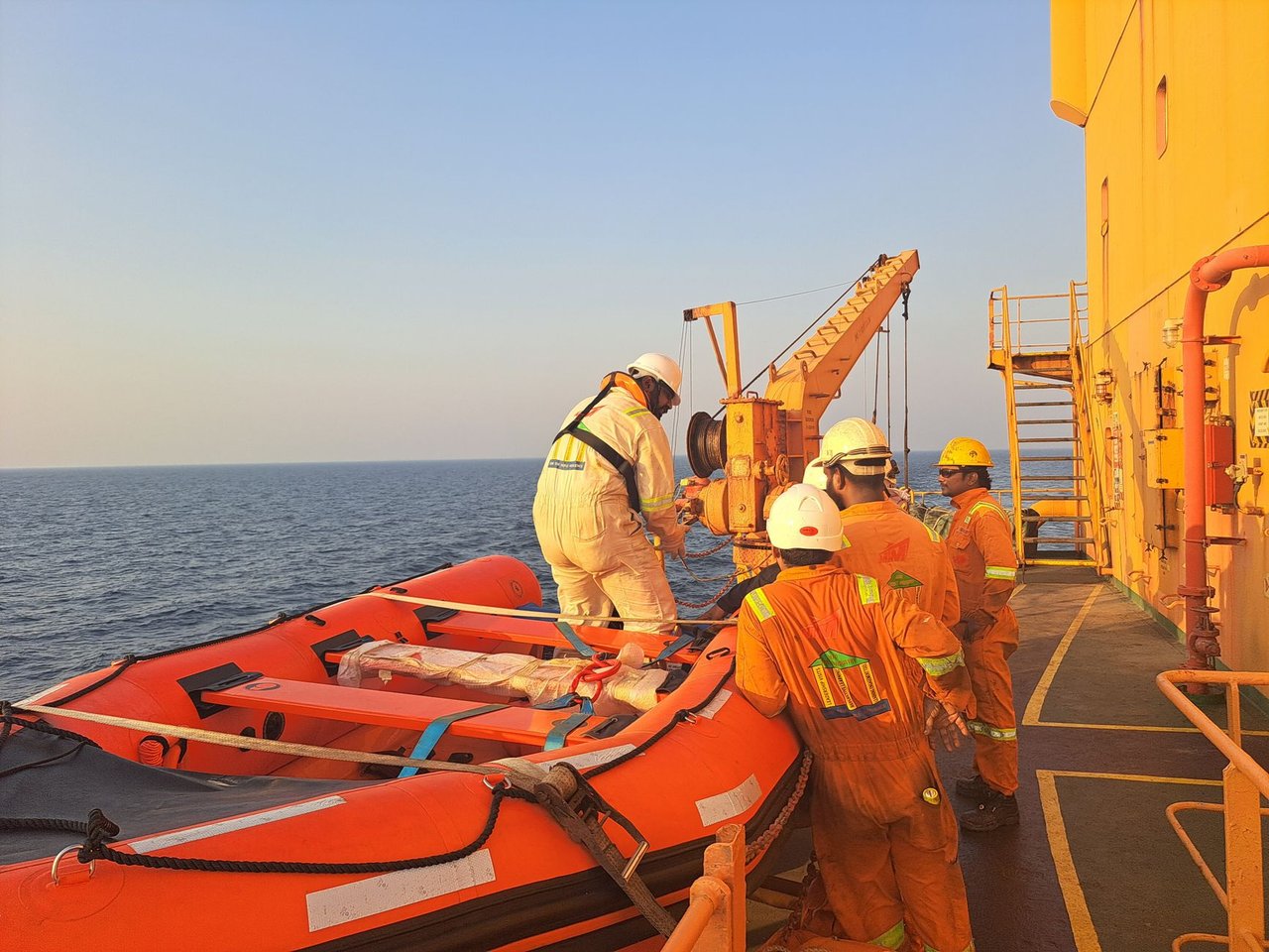 Tripulantes usando equipamentos de proteção preparam um bote salva-vidas durante um exercício de segurança marítima a bordo de um navio.