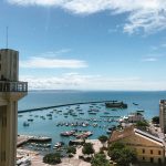 Vista do porto de Salvador com embarcações e o Elevador Lacerda ao fundo.