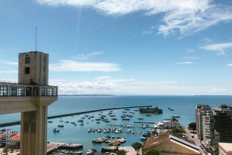 Vista do porto de Salvador com embarcações e o Elevador Lacerda ao fundo.